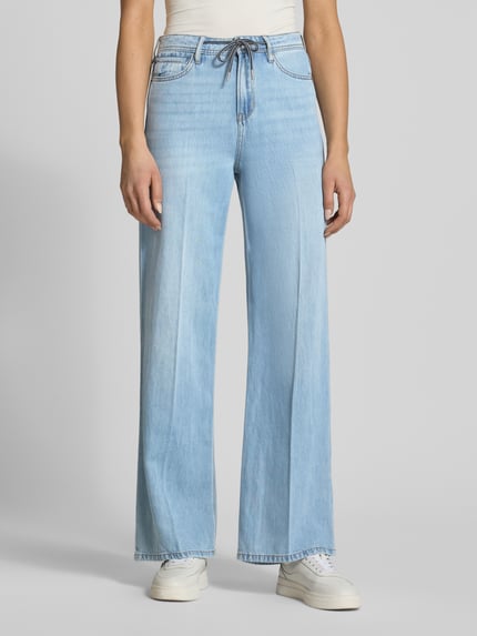 Vrouwenmodel draagt Wide Leg Jeans uit Lyocell-Baumwoll-Mix model 'SURI' van s.Oliver RED LABEL in denimlook met 5-pocketmodel, mid taille, riemlussen, tunnelkoord, knoop- en ritssluiting, labelpatch; lichte blauwe kleur, gladde textuur. Volledige lichaamsaanzicht van voren.