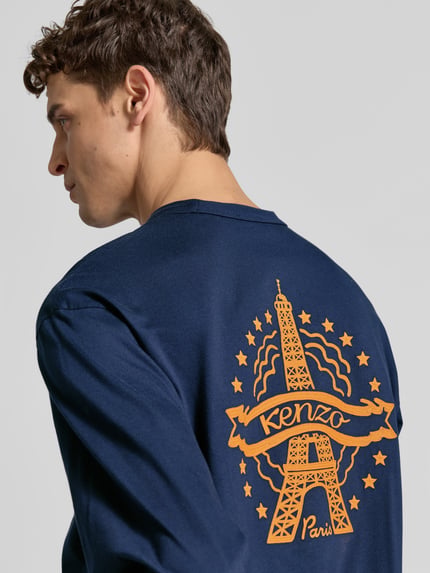 Männermodel trägt Longsleeve mit Label-Stitching von Kenzo aus reiner Baumwolle in Dunkelblau mit orangefarbenem Print, Ganzkörperansicht Rückansicht. Rückenlänge bei Größe M: 75 cm, gerader Schnitt, Rundhalsausschnitt.