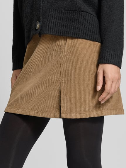 Vrouwenmodel draagt lichtbruine corduroy rok met fijne ribstructuur, Dames minirok van VERO MODA Körpernaher Mini-Rock aus katoenmix model 'LULA', detailopname onderste lichaamsdeel