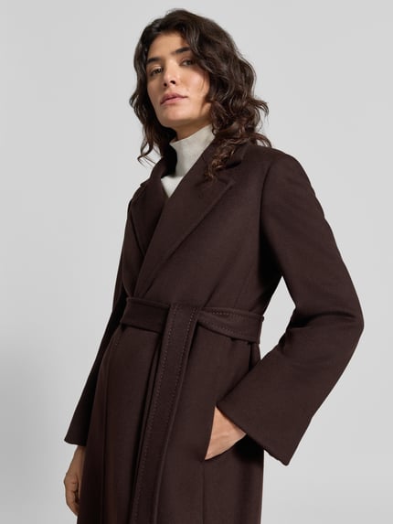 Frauenmodel trägt Mantel mit Taillengürtel Modell 'MCORUNAWAY1' von MAX&Co, melangiert, Fischgräten-Muster, Longline, Reverskragen, Label-Schriftzug, Gehschlitz, Bindegürtel, Nahaufnahme Oberkörper.