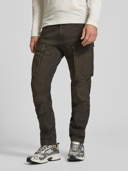 Männermodel trägt Regular Tapered Cargohose aus Baumwoll-Mix Modell 'Rovic' von G-Star RAW in Dunkelbraun, Cargotaschen, Ganzkörperansicht von vorne.