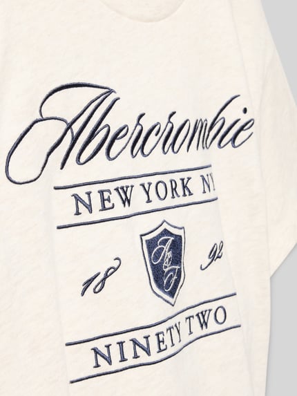 Produktfoto, Regular Fit T-Shirt mit Logo-Stitching von Abercrombie&Fitch, cremefarbener Baumwoll-Mix, navyblaue Stickerei, Rundhalsausschnitt, Textur aus weichem Stoff