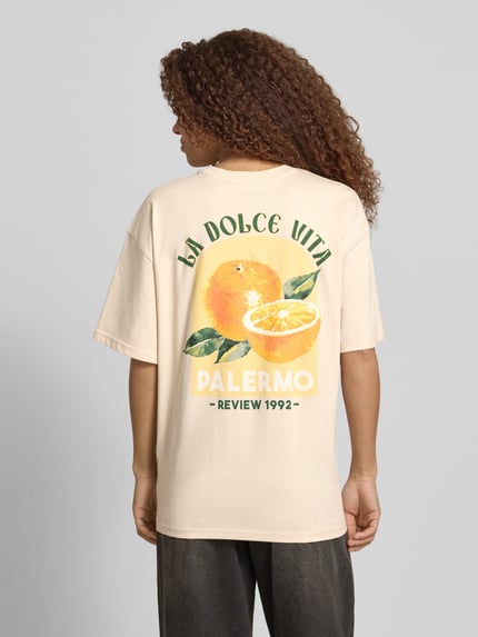 Vrouwenmodel draagt T-shirt met rückseitigem motiefprint van REVIEW, puur katoen, oversized fit, ronde hals, ruglengte maat S 68 cm, Ganzkörperansicht Rückansicht.