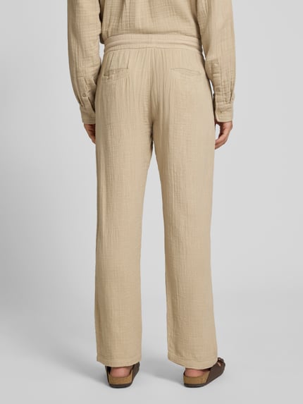 Mężczyznamodel nosi Straight Fit Sweatpants in Musselin-Optik od Lindbergh z bawełny, krój straight fit, muślin, elastyczny pas z tunelem, szerokość w rozmiarze M: 41 cm, długość wewnętrzna nogawki: 81 cm, beżowy kolor, widoczne delikatne faktury tkaniny, spodnie o prostym kroju, widok całej sylwetki z tyłu