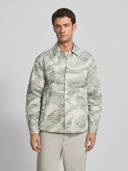 Männermodel trägt Regular Fit Hemdjacke mit Rumpftunnelzug Modell 'LELDON' von BOSS Orange, Camouflage-Muster, Ganzkörperansicht von vorne.
