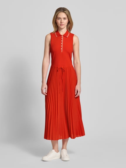 Vrouwenmodel draagt 'Tailliertes Freizeitkleid aus Baumwoll-Mix' van Tommy Hilfiger, effen rood, getailleerd, midilengte, plissé, polokraag, knoopsluiting, brede bandjes, plissé knitwear, katoenmix. Volledig frontaal, totaalbeeld.