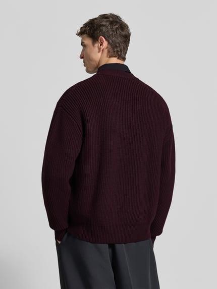 Männermodel trägt dunkelroten Relaxed Fit Pullover aus reiner Wolle von SEIDENSTICKER STUDIO, Oversized-Strick, Rückansicht, Ganzkörperansicht Rückansicht