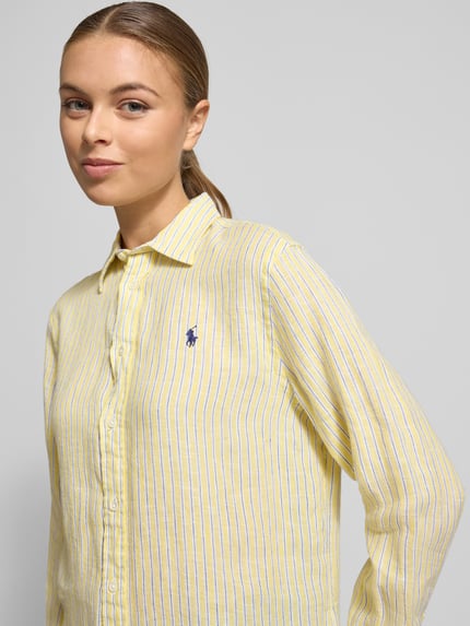 Kobiece modelka nosi Bluzka koszulowa z listwą guzikową od Polo Ralph Lauren, wykonana z lnu, luźny krój, kołnierzyk koszulowy, wyhaftowane logo, żółte pasy, długość tyłu 70 cm, długość rękawa 62 cm, widok na górę ciała z przodu.