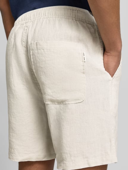Männermodel trägt Shorts mit Eingrifftaschen Modell 'JABARI' von Samsøe Samsøe in Beige, reine Baumwolle, elastischer Bund, Ganzkörperansicht Rückansicht.