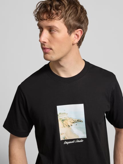Männermodel trägt schwarzes T-Shirt mit Rundhalsausschnitt Modell 'JORNORREBRO' von Jack & Jones, Print vorne, reine Baumwolle, Nahaufnahme Oberkörper.