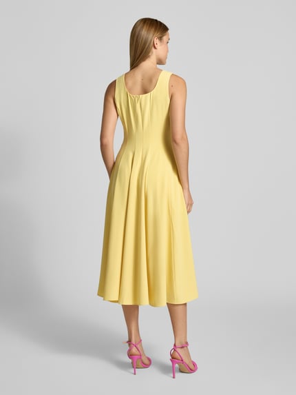 Männermodel trägt Midikleid mit Rundhalsausschnitt Modell 'ARLOTT' von Ted Baker, żółty kolor, szerokie ramiączka, zamek z tyłu, szerokość w rozmiarze 36: 44 cm, długość tyłu 107 cm, A-linia, widok całej sylwetki z tyłu.