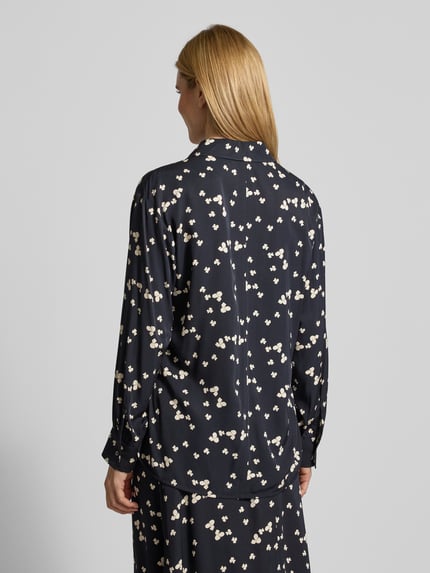 Frauenmodel trägt Oversized Langarmbluse aus reiner Viskose von Marc O'Polo mit floralem Allover-Muster, dunkle Twill-Optik, Hemdblusenkragen, Label-Stitching, Knopfleiste, Manschetten, abgerundet, asymmetrisch, mit Seitenschlitzen, Ganzkörperansicht Rückansicht.