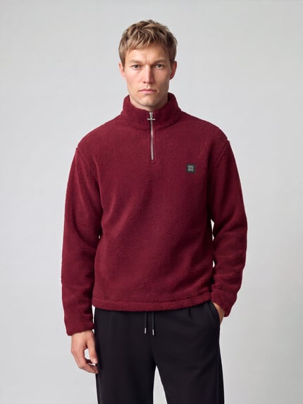 Männermodel trägt Sweatshirt mit Logo-Detail Modell 'Derylong' von HUGO in Bordeaux, Fleece-Struktur, Reißverschluss, Ganzkörperansicht von vorne.