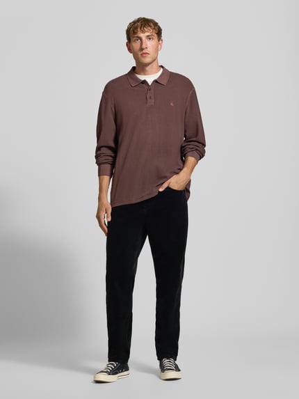 Männermodel trägt Straight Fit Hose aus reiner Baumwolle in Cord-Optik von Carhartt Work In Progress, schwarze Farbe, 5-Pocket-Design, Ganzkörperansicht von vorne.