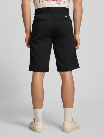 Männermodel trägt Bermudas mit französischen Eingrifftaschen von Dickies aus Reine Baumwolle, Straight Fit, klassisch schwarz, Ganzkörperansicht Rückansicht.