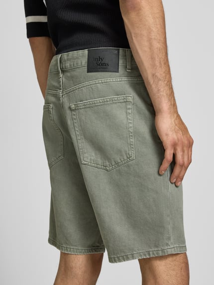 Männermodel trägt Regular Fit Jeansshorts aus reiner Baumwolle Modell 'EDGE' von Only & Sons in Denim-Optik, Label-Patch, Nieten, 5-Pocket-Design, Detailaufnahme Rückansicht.
