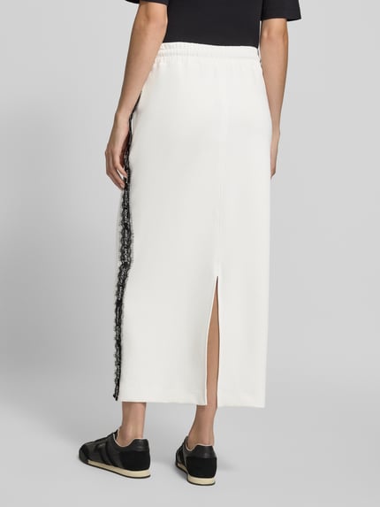Vrouwenmodel draagt Midi-Rok uit katoenmix van Marc Cain, effen kleuren, kant, koordjes, elastische boord, zijsplitten, mix van katoen, geheel achteraanzicht.