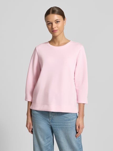 Vrouwenmodel draagt Comfort Fit Sweatshirt aus Modal-Mix van s.Oliver RED LABEL in effen lichtroze scuba-materiaal, ronde hals, 3/4-mouw, met splitten aan de zijkant, vooraanzicht, bovenlichaam close-up.