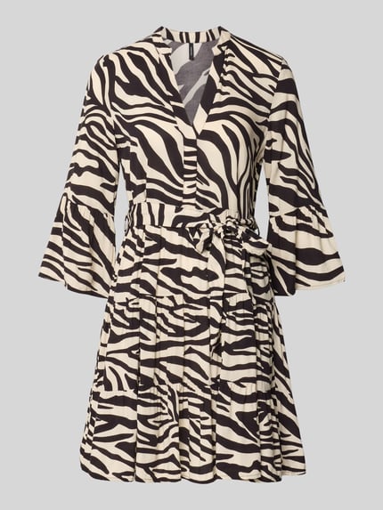 Produktfoto, Tailliertes Tunikakleid aus reiner Viskose Modell 'MELBA' von Vero Moda mit Optik:Allover-Muster in Schwarz und Creme, Trompetenärmel, V-Ausschnitt, Mini-Länge, Bindegürtel und Volant-Saum, Material: Viskose
