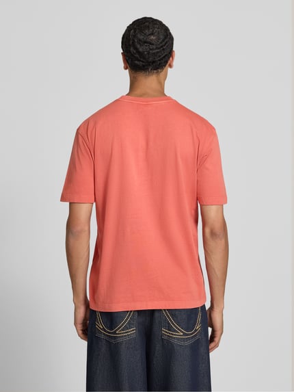 Männermodel trägt Regular Fit T-Shirt aus reiner Baumwolle Modell 'John Tee' von Pepe Jeans in Koralle, Ganzkörperansicht Rückansicht. Herren T-Shirt von Pepe Jeans.