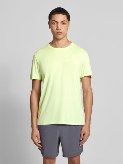 Männermodel trägt TRAINING T-Shirt mit Label-Detail Modell van PUMA PERFORMANCE, recht model, ronde hals, labeldetail, met korte mouwen, ruglengte maat M 73 cm, heren T-shirt, effen lichtgroen, gladde textuur, Ganzkörperansicht von vorne.