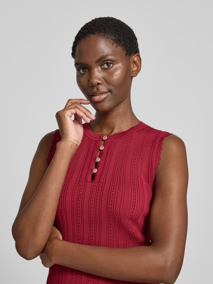 Frauenmodel trägt Stricktop in Pointelle-Strick mit kurzer Knopfleiste von GUESS, Viskose-Mix, Rundhalsausschnitt, Nahaufnahme Oberkörper.