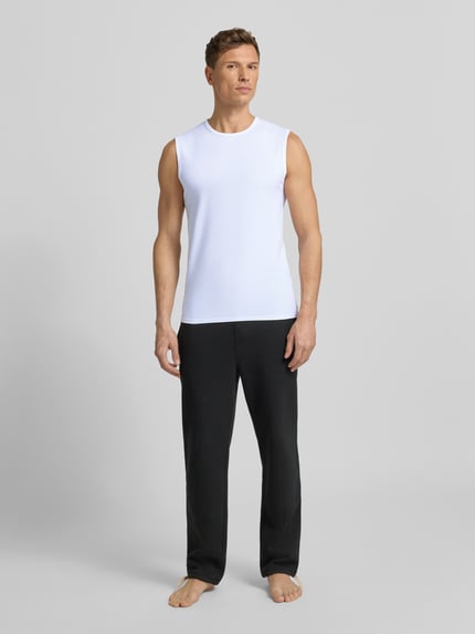 Męski model nosi Unterhemd mit Rundhalsausschnitt von MCNEAL, mieszanka bawełny i elastanu, krój slim fit, szerokie ramiączka, biel, gładka faktura, całkowity widok z przodu.