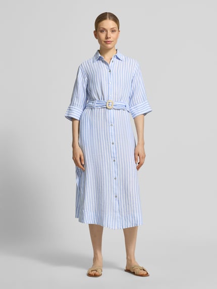 Modelka kobieca nosi Hemdblusenkleid aus Leinen mit Gürtel od Christian Berg Woman, niebiesko-białe paski, krój taliowany, pasek, długość midi, guzikowanie, kołnierz koszulowy, rękaw 35 cm, długość tyłu 118 cm, szerokość w rozmiarze 36: 45 cm, widok całej sylwetki z przodu.