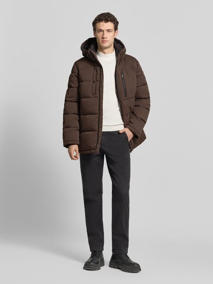 Männermodel trägt Steppjacke mit vielen Reißverschlusstaschen von s.Oliver RED LABEL in Dunkelbraun mit Struktur, Ganzkörperansicht von vorne.