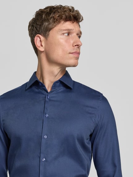 Männermodel trägt Slim Fit Businesshemd mit Kentkragen von Seidensticker, unifarben, strukturierte Webware, Nahaufnahme Oberkörper.