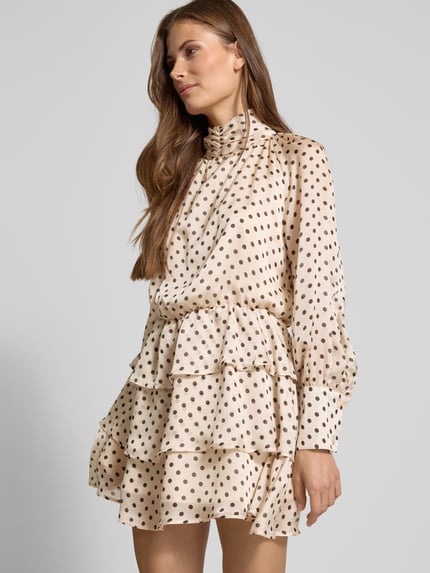 Frauenmodel trägt Cocktailkleid im Stufen-Look mit Stehkragen von Rinascimento aus Satin, beige mit braunen Punkten, tailliert, Minikleid, Nahaufnahme Oberkörper.