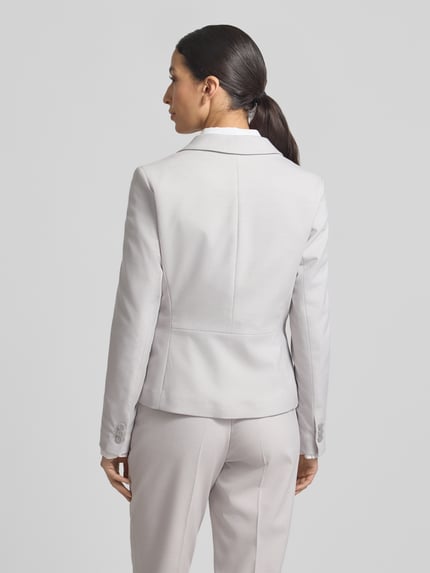 Vrouwenmodel draagt Slim Fit Blazer met reverskraag van More & More, materiaalmix met viscose, paspelzakken, ruglengte 57 cm, borstwijdte 46 cm, mouwlengte 64 cm, knoopsluiting, kleur lichtgrijs, geheelopname rugaanzicht