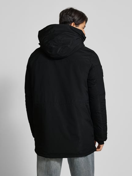 Männermodel trägt schwarzen Parka mit Kapuze von Superdry, Material-Mix mit Stretch, Regular Fit, Rückenansicht, Ganzkörperansicht Rückansicht.