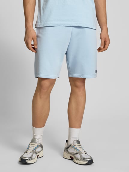 Männermodel trägt Regular Fit Shorts mit Label-Stitching von REVIEW aus Baumwoll-Mix in Hellblau, elastischer Bund, Nahaufnahme Oberschenkel.