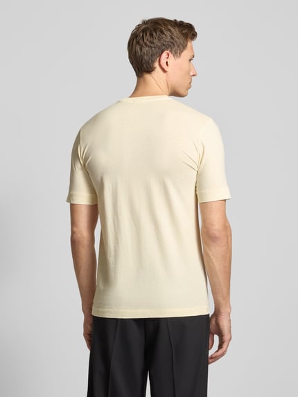 Männermodel trägt T-Shirt mit geripptem Rundhalsausschnitt von Drykorn in Creme, reine Baumwolle, Regular Fit, Rückenlänge 70 cm, Ganzkörperansicht Rückansicht.