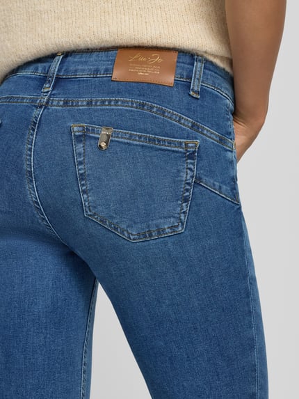 Frauenmodel trägt Skinny Fit Jeans aus elastischem Baumwoll-Mix Modell 'MONROE' von Liu Jo White, blaue Textur, Detailaufnahme