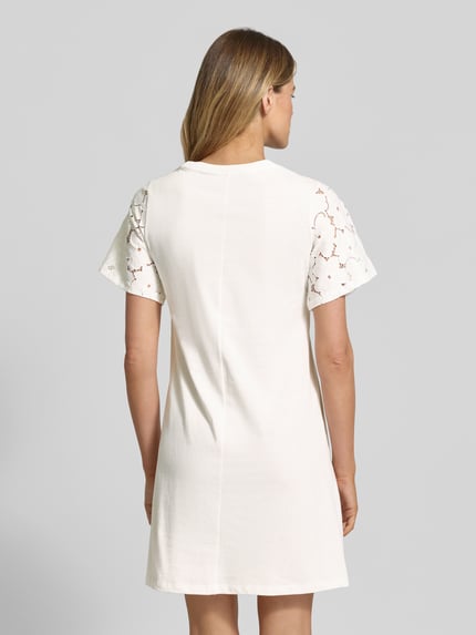 Vrouwenmodel draagt vrijetijdsjurk van puur katoen model 'VILLA' van Vero Moda, look: effen, licht uitlopend, met kant, minilengte, ronde hals, korte mouw, rechte zoom, jersey materiaalverwerking, Ganzkörperansicht Rückansicht.