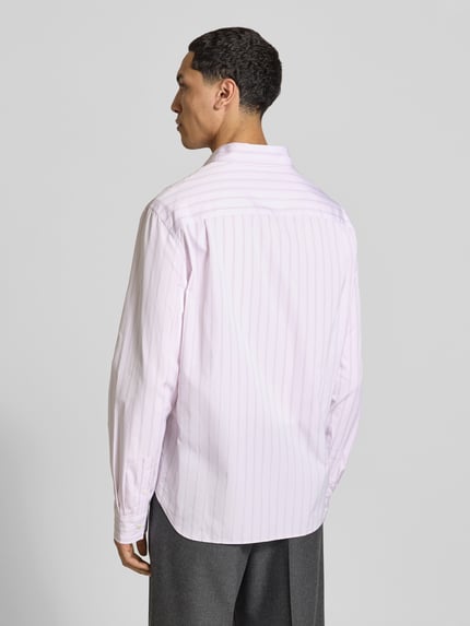 Męski model trägt Relaxed Fit Freizeithemd aus bawełny von MAISON KITSUNÉ, jasnoróżowe z delikatnym wzorem w paski, listwa guzikowa na całej długości, nakładana brustasza, krój z długim rękawem, długość tyłu w rozmiarze M: 74 cm, szerokość w rozmiarze M: 49 cm, długość rękawów w rozmiarze M: 68 cm, widok całej sylwetki z tyłu.