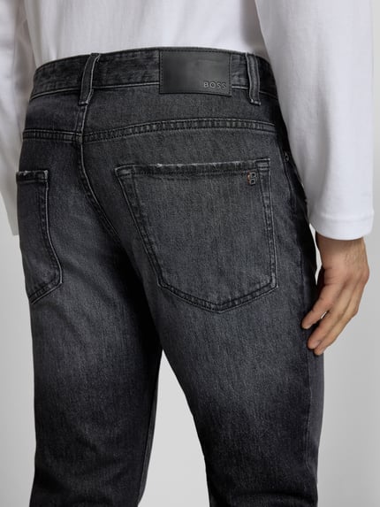 Męski model nosi Regular Fit Jeansy z bawełnianej mieszanki Model 'RE.MAINE BO' od BOSS Orange, efekt: jednolity kolor, detal: naszywka z logo, denim, 5 kieszeni. Detaliczne ujęcie tylnej części.