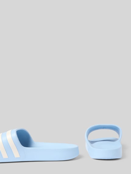 Produktfoto, hellblaue Badeschuhe mit Label-Prägung Modell 'ADILETTE AQUA' von adidas Sportswear, flache Sohle, strukturierte Textur, Signature-Streifen, Peep Toe, unifarbene Optik.