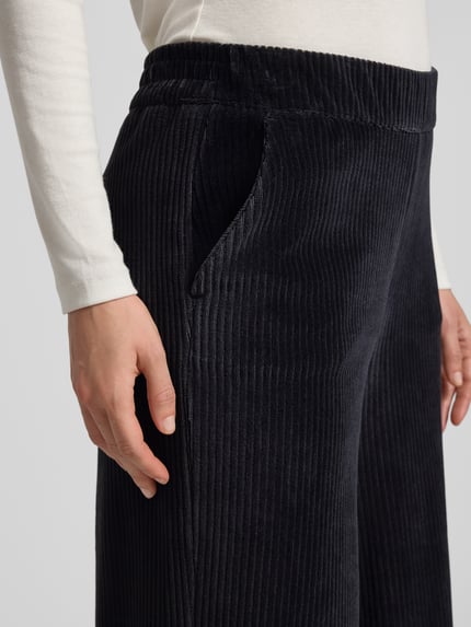 Vrouwenmodel draagt Cordhose met Eingrifftaschen und elastischem Bund van Smith and Soul, zwart, wijde pijpen, detailopname heup.