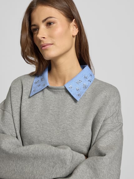 Vrouwenmodel draagt 'Sweatshirt mit Hemdblusenkragen' van Liu Jo White, grijs, katoenmix met stretch, losse pasvorm, geribde boorden, close-up bovenlichaam.