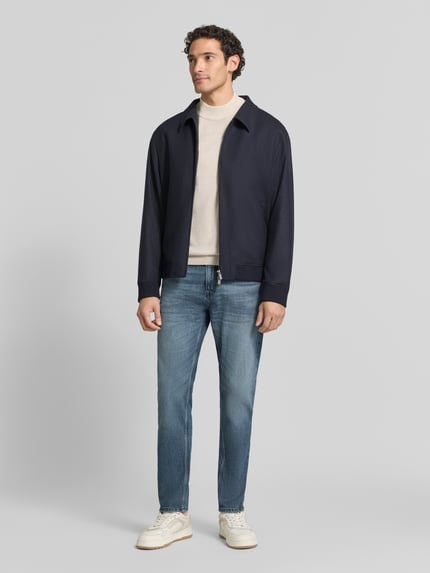 Männermodel trägt Regular Fit Jeans mit Used Waschung Modell 'ONYX SMU' von BOSS Orange in Medium Wash Denim mit 5-Pocket-Design, Ganzkörperansicht von vorne.