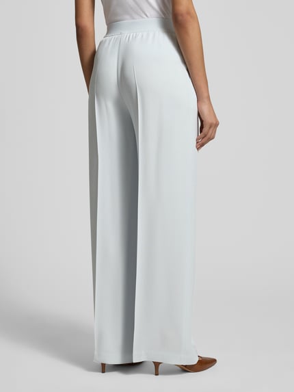 Frauenmodel trägt Weite Hose aus reiner Viskose Modell 'TIANA10' von BOSS, unifarben, Wide Leg, elastischer Bund, Rückansicht Ganzkörperansicht.