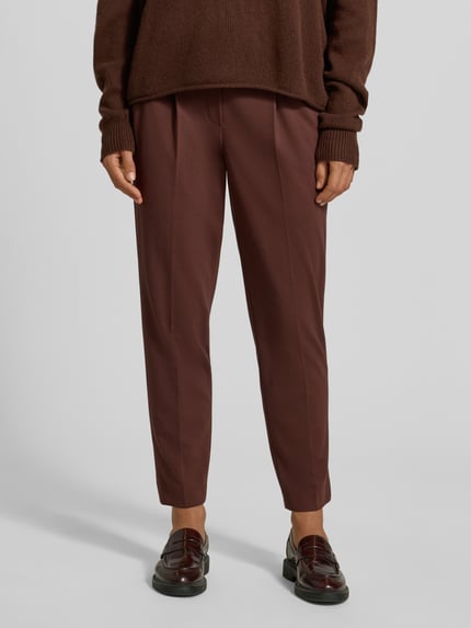 Frauenmodel trägt Straight Fit Hose aus Viskose-Mix mit Bundfalten von Luisa Cerano in Dunkelbraun, Detailaufnahme der Beinpartie, elastischer Bund, verkürzte Passform, dezente Textur.