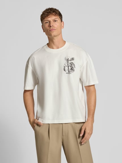 Männermodel trägt Relaxed Fit T-Shirt aus reiner Baumwolle Modell 'SERAPH' von AllSaints, weiß mit Motiv-Print, glatte Textur, Ganzkörperansicht von vorne, Rückenlänge bei Größe M 65 cm.