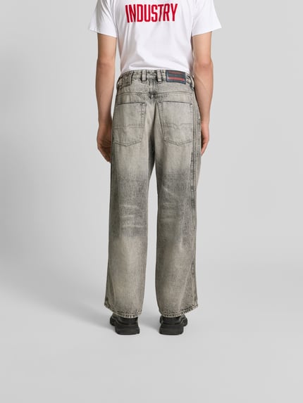 Männermodel trägt Loose Fit Jeans aus Baumwoll-Mix von Diesel in grauer Waschung mit 5-Pocket-Design und Label-Detail, Ganzkörperansicht Rückansicht. Innenbeinlänge 80 cm, Bundweite 44 cm.