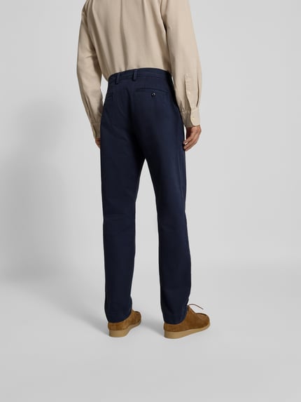 Männermodel trägt Chino mit Gesäßtaschen von Officine Générale in Dunkelblau, Reine Baumwolle, Gerader-Schnitt, Ganzkörperansicht Rückansicht.