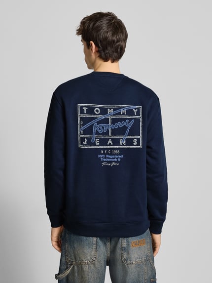 Männermodel trägt Regular Fit Sweatshirt aus reiner Baumwolle von Tommy Jeans in Dunkelblau mit Label Print, Ganzkörperansicht Rückansicht.