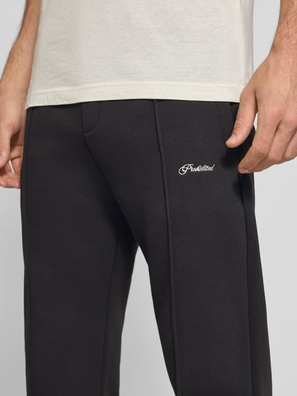 Männermodel trägt Sweatpants mit elastischem Bund und Label-Stitching von PROHIBITED, Baumwoll-Mix, Loose Fit, Nahaufnahme Oberschenkel.